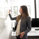 Professional woman writing on a whiteboard in an office environment, focusing on ideas.